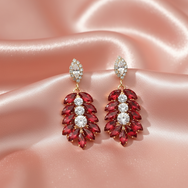 Red and gold earrings on a pink satin background